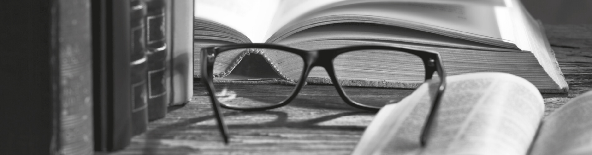 Černobílý obrázek knih a brýlí